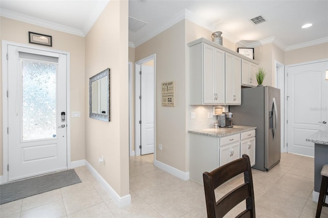 kitchen with white cabinetry, decorative backsplash, ornamental molding, stainless steel fridge with ice dispenser, and light stone countertops