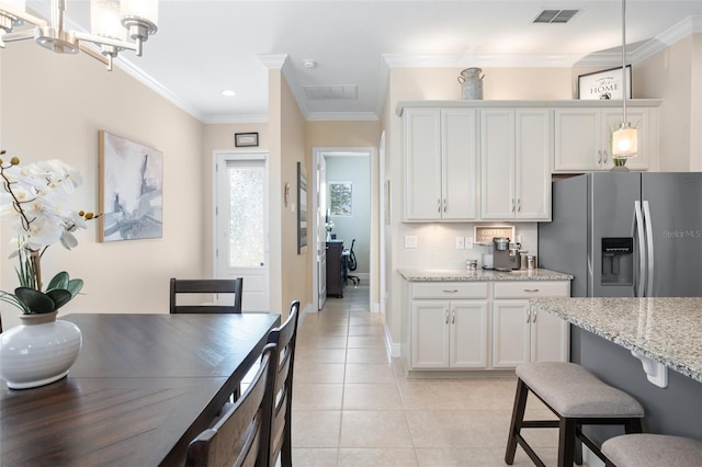 kitchen with light tile patterned floors, white cabinetry, stainless steel refrigerator with ice dispenser, light stone countertops, and decorative light fixtures