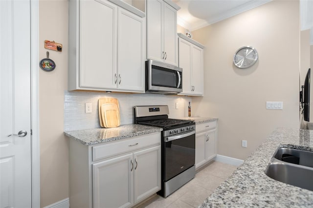 kitchen with white cabinetry, stainless steel appliances, light stone counters, and backsplash