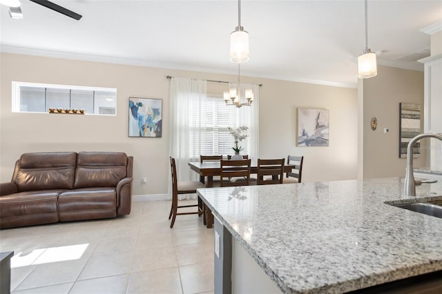 kitchen with pendant lighting, sink, ornamental molding, light tile patterned floors, and light stone countertops