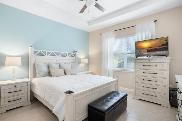 bedroom with light tile patterned flooring, ceiling fan, and a tray ceiling