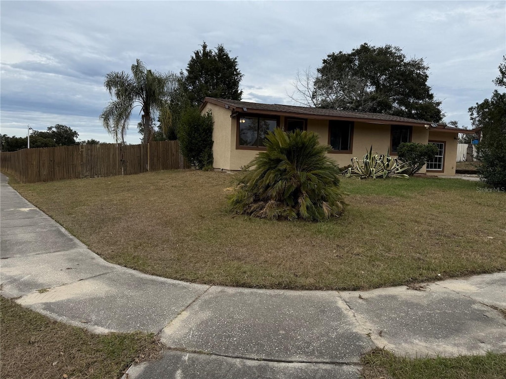 exterior space with a yard, fence, and stucco siding