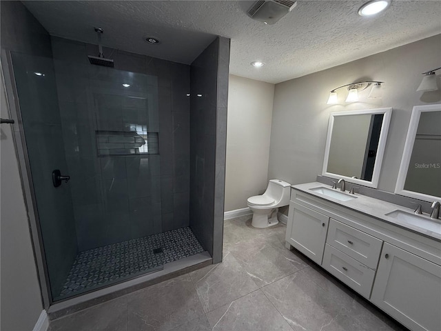 bathroom featuring vanity, a tile shower, a textured ceiling, and toilet