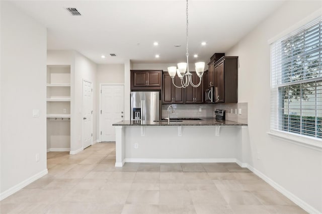 kitchen featuring dark stone counters, a kitchen bar, appliances with stainless steel finishes, and decorative light fixtures