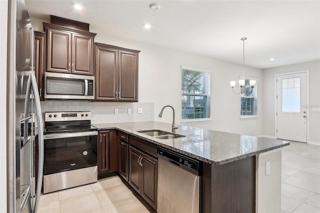 kitchen featuring sink, kitchen peninsula, light stone countertops, and appliances with stainless steel finishes