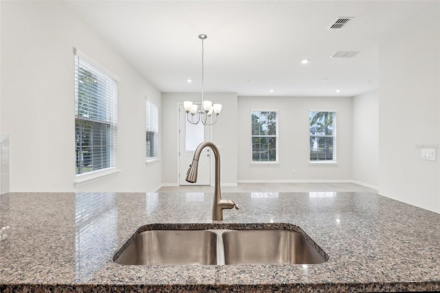 kitchen featuring stone countertops, sink, hanging light fixtures, and a wealth of natural light