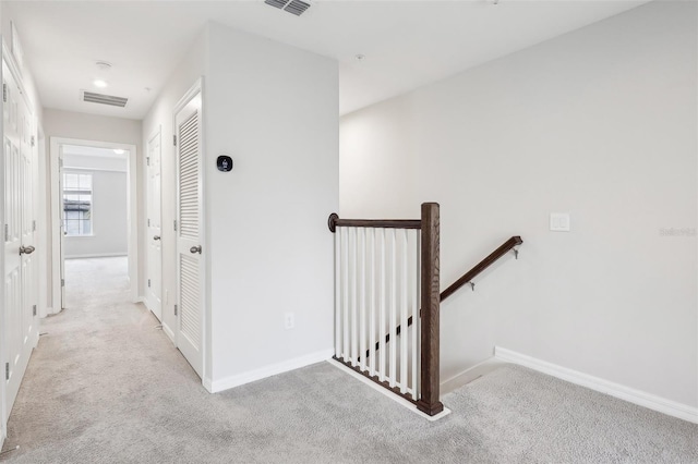 hallway featuring light colored carpet