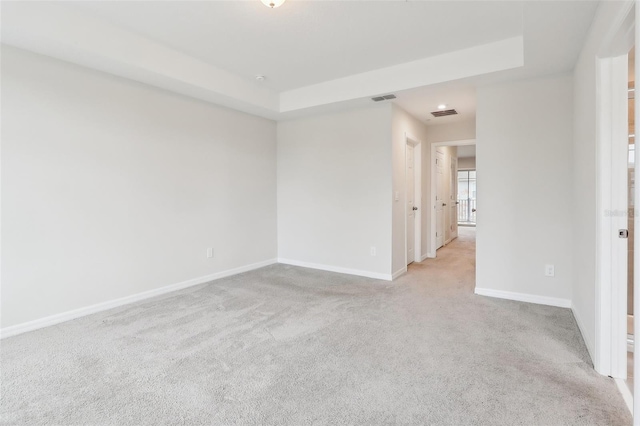 carpeted spare room with a tray ceiling