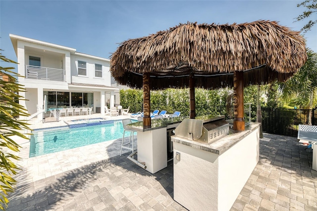 view of pool featuring a bar, exterior kitchen, a patio area, and grilling area