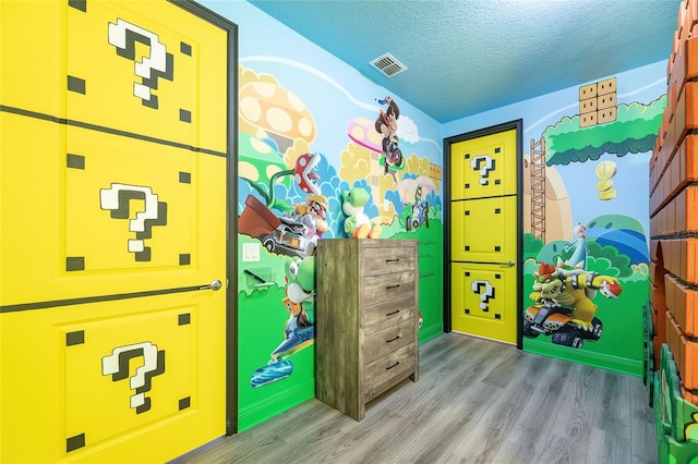 recreation room with light hardwood / wood-style flooring and a textured ceiling