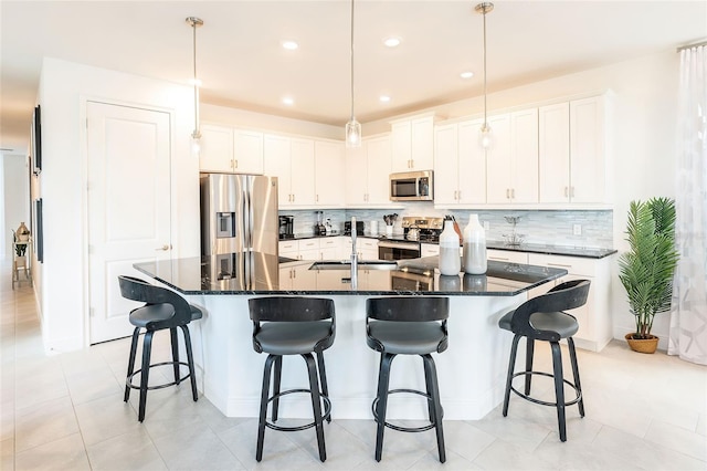 kitchen with pendant lighting, appliances with stainless steel finishes, white cabinetry, sink, and a large island