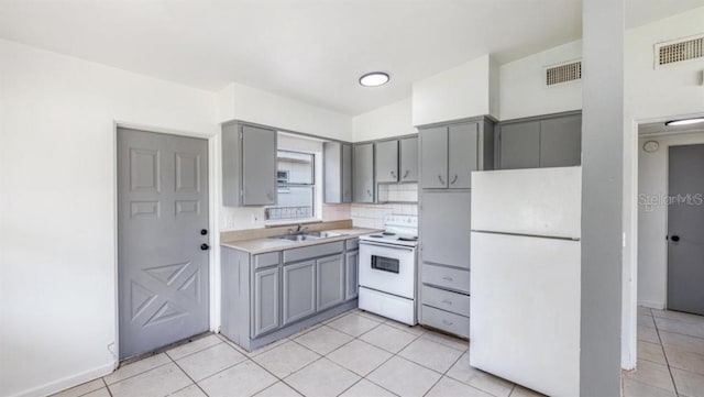 kitchen featuring white appliances, decorative backsplash, sink, light tile patterned floors, and gray cabinetry