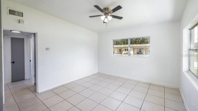 tiled spare room featuring ceiling fan and a healthy amount of sunlight