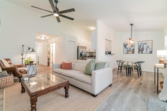 living room featuring ceiling fan, lofted ceiling, and light wood-type flooring