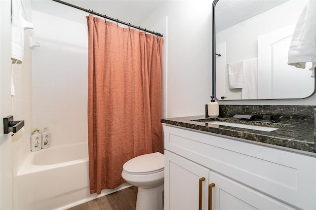 full bathroom featuring hardwood / wood-style flooring, vanity, toilet, shower / bathtub combination with curtain, and a textured ceiling