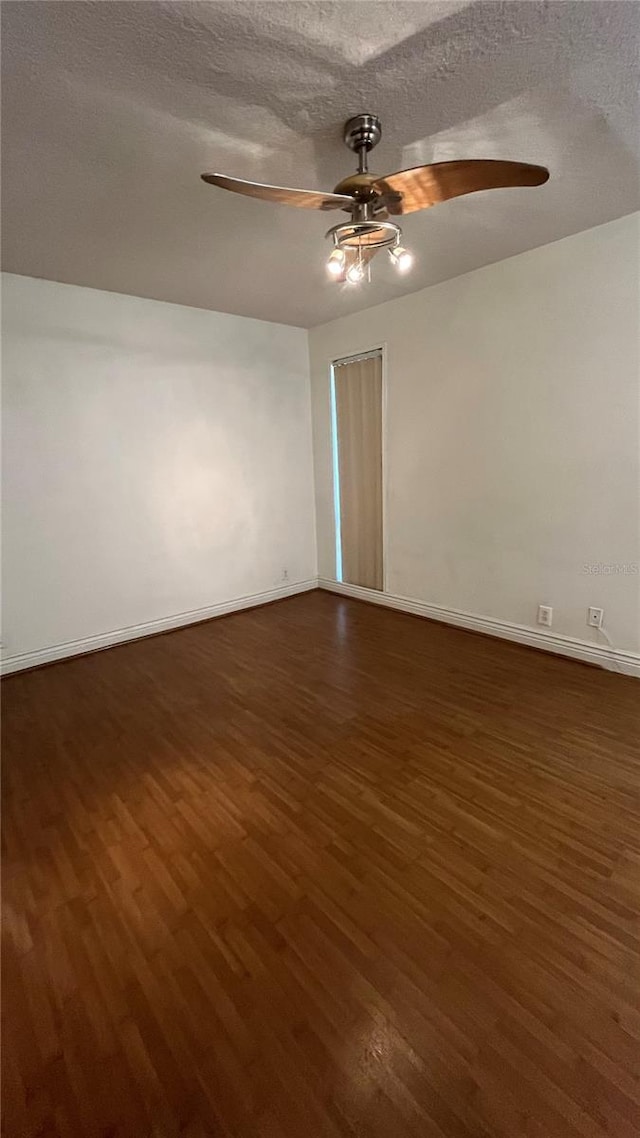 empty room with a textured ceiling, dark wood-type flooring, and ceiling fan