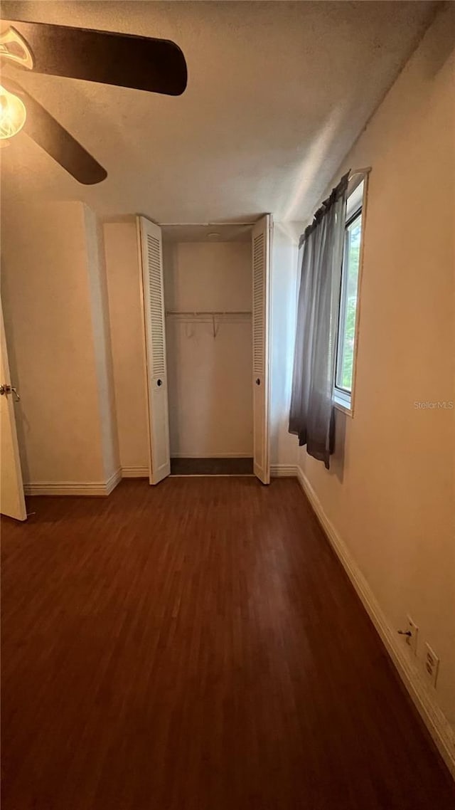 unfurnished bedroom featuring dark hardwood / wood-style floors, ceiling fan, and a closet