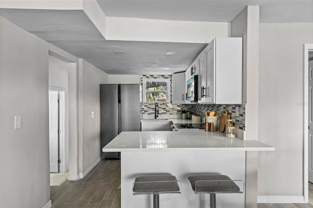 kitchen with kitchen peninsula, sink, a breakfast bar area, and tasteful backsplash