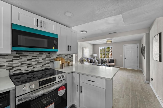 kitchen with kitchen peninsula, white cabinets, a textured ceiling, decorative backsplash, and stainless steel electric range