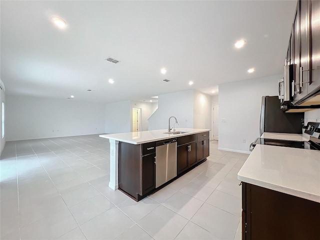 kitchen featuring dark brown cabinetry, stainless steel appliances, an island with sink, sink, and light tile patterned floors