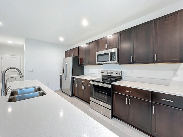 kitchen featuring sink, stainless steel appliances, dark brown cabinets, and light tile patterned floors