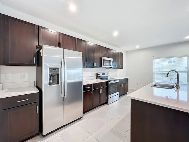 kitchen with sink, light tile patterned floors, stainless steel appliances, and dark brown cabinets