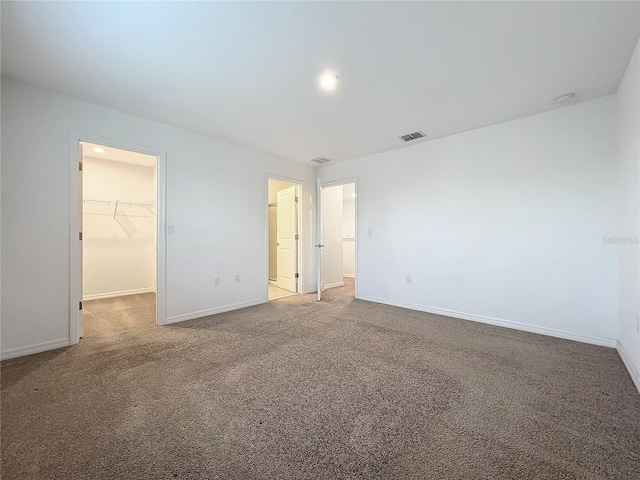 unfurnished bedroom with a walk in closet, carpet floors, and a closet