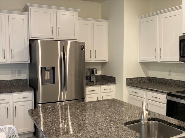 kitchen featuring white cabinetry, sink, stainless steel appliances, and dark stone counters