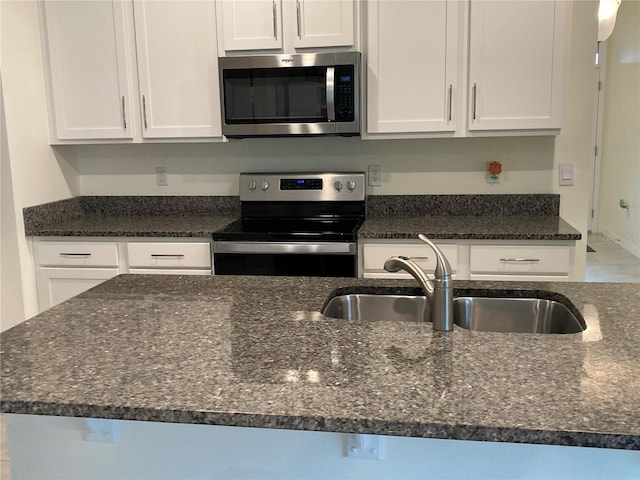 kitchen with white cabinetry, sink, dark stone counters, and appliances with stainless steel finishes