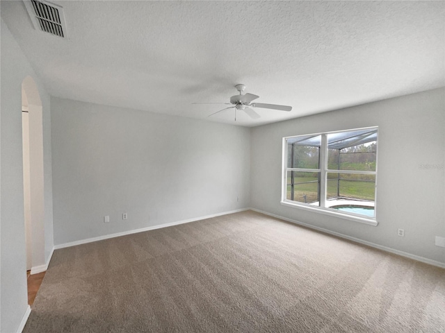 unfurnished room featuring ceiling fan, a textured ceiling, and dark carpet