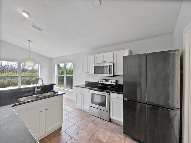 kitchen featuring vaulted ceiling, white cabinetry, sink, pendant lighting, and stainless steel appliances