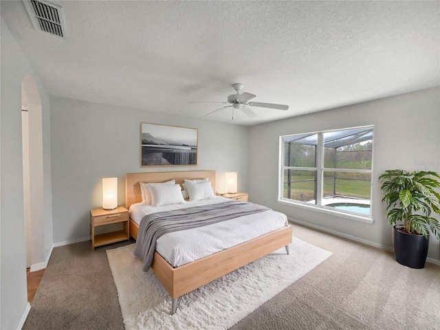 bedroom featuring light carpet, a textured ceiling, and ceiling fan