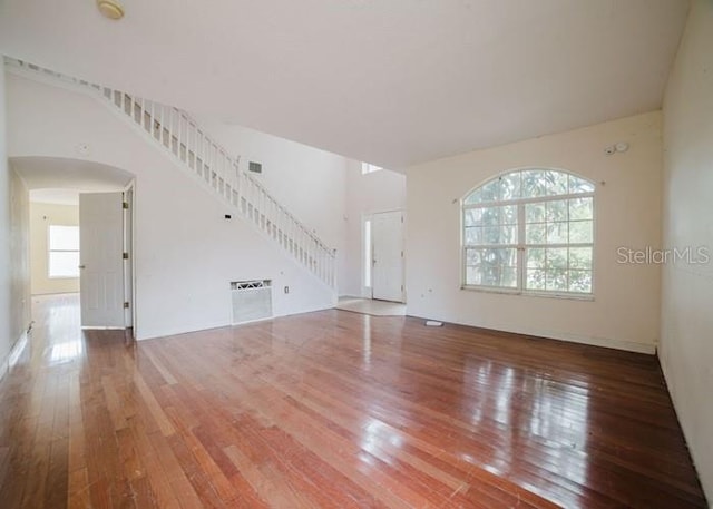 1010 Embrun Ct, Kissimmee, FL 34759 - unfurnished living room with stairs, arched walkways, visible vents, and hardwood / wood-style floors