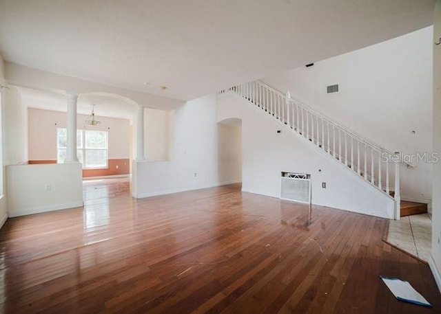 1010 Embrun Ct, Kissimmee, FL 34759 - unfurnished living room with visible vents, arched walkways, stairway, ornate columns, and hardwood / wood-style floors