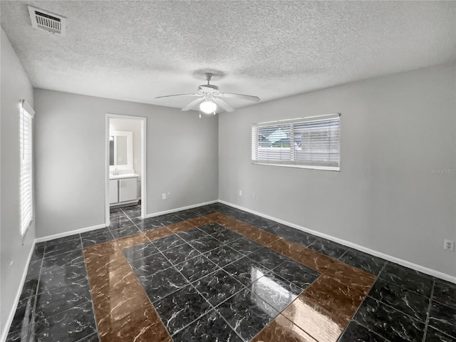 spare room featuring ceiling fan, a textured ceiling, and a healthy amount of sunlight