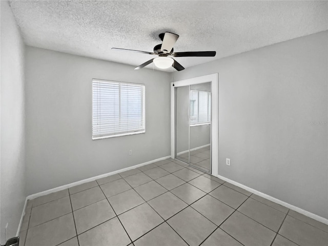 unfurnished bedroom featuring light tile patterned flooring, a textured ceiling, a closet, and ceiling fan