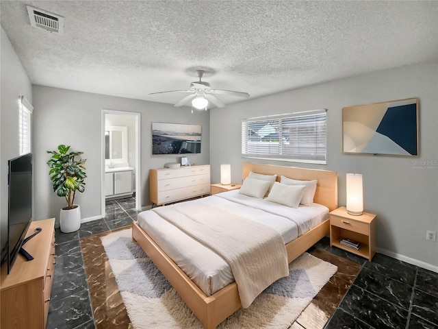 bedroom featuring ceiling fan, multiple windows, ensuite bath, and a textured ceiling