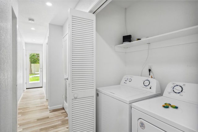 laundry area with light hardwood / wood-style floors and washing machine and clothes dryer