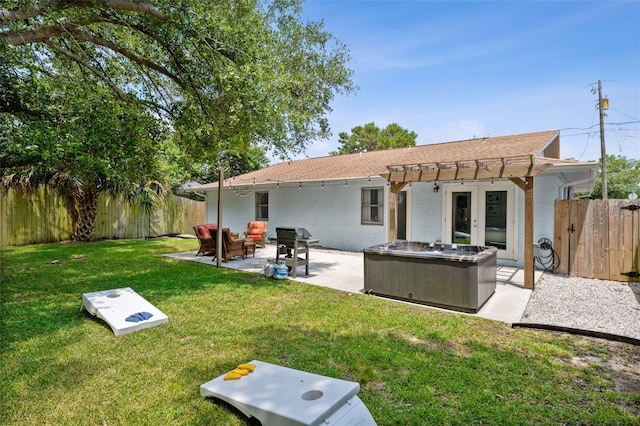 rear view of house with a pergola, french doors, a hot tub, a patio area, and a yard