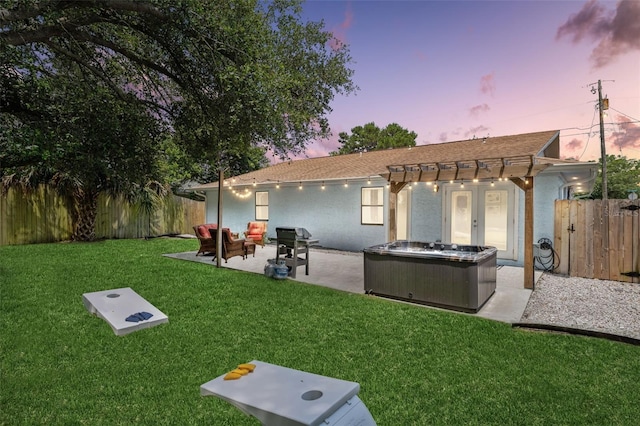 back house at dusk with a patio area, a hot tub, french doors, a yard, and an outdoor hangout area