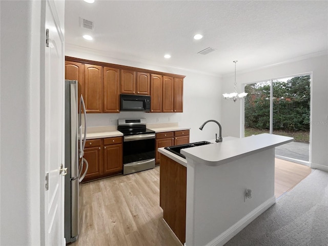 kitchen featuring sink, crown molding, hanging light fixtures, stainless steel appliances, and a center island with sink