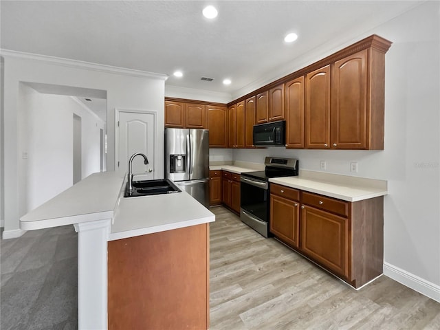 kitchen featuring appliances with stainless steel finishes, sink, ornamental molding, light hardwood / wood-style floors, and a center island with sink