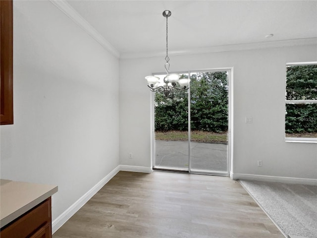 unfurnished dining area featuring crown molding, light wood-type flooring, and an inviting chandelier