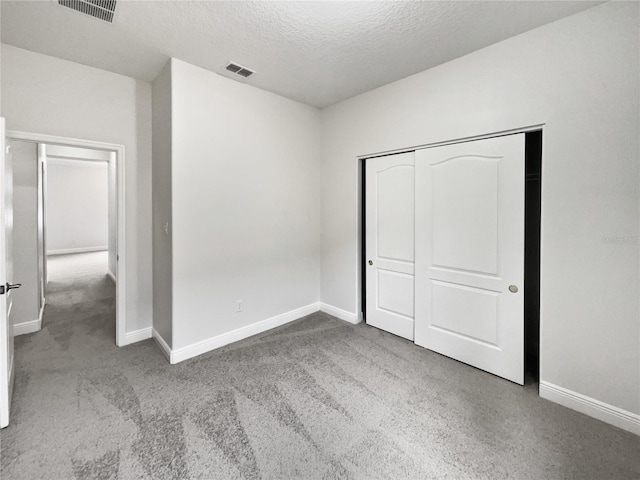 unfurnished bedroom featuring carpet flooring, a closet, and a textured ceiling