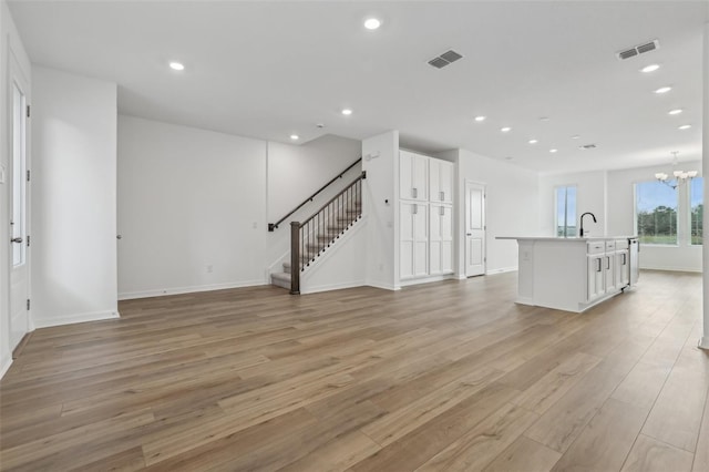 unfurnished living room with an inviting chandelier and light wood-type flooring