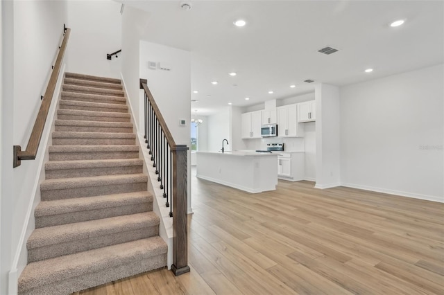 staircase with sink and hardwood / wood-style floors