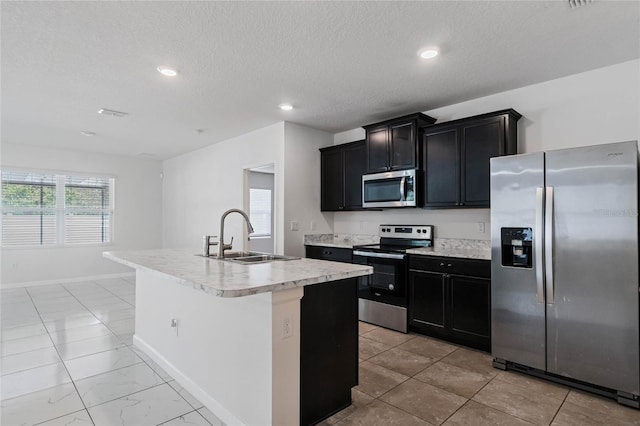 kitchen with stainless steel appliances, sink, a kitchen island with sink, and a textured ceiling