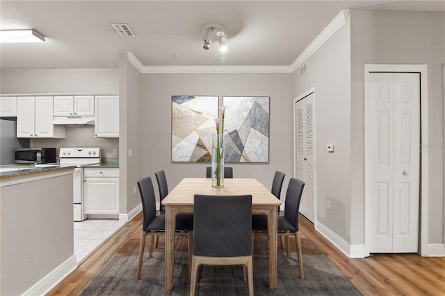 dining area with ornamental molding and light hardwood / wood-style flooring