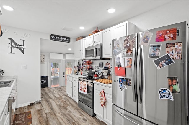 kitchen featuring appliances with stainless steel finishes, sink, white cabinets, light hardwood / wood-style floors, and french doors