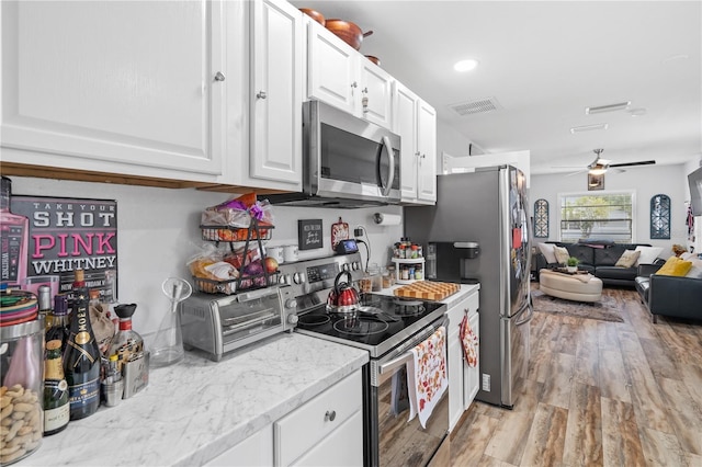 kitchen featuring white cabinetry, light hardwood / wood-style flooring, ceiling fan, stainless steel appliances, and light stone countertops